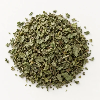 Loose dried lemon balm on a warm-white background.