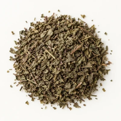 Loose dried tulsi (holy basil) on a warm-white background.